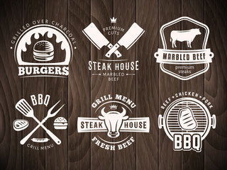 Fototapety  BBQ, burger, odznaki grillowe. Zestaw logo wektor grilla. Retro emblematy dla steków lub baru grillowego na drewniane tło.