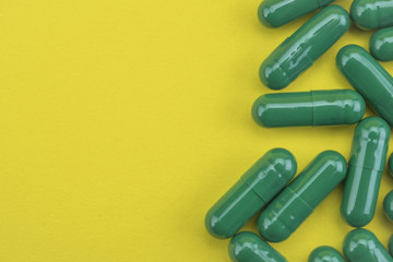 Green pills capsules medicine on yellow background
