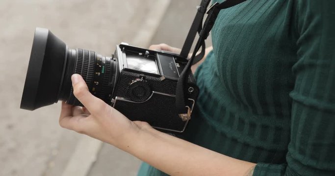 Old medium format camera in the hands of a hipster girl, close-up, film camera