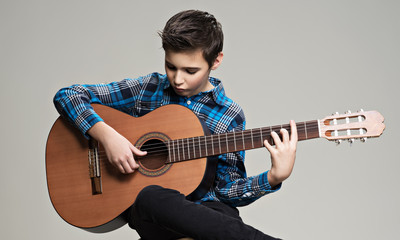 Caucasian  boy playing on acoustic guitar.
