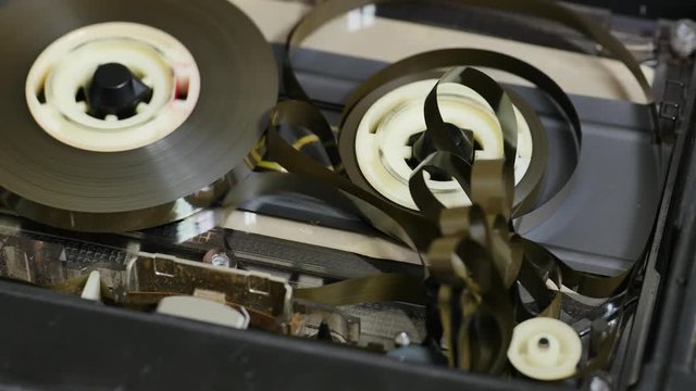Tape loops and tangling in a deck cassette player when the take up spool stops or running slower than the other. Close up 4K static shot. Audio cassette tape in use sound playback