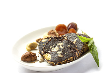 Chocolate cut sausage with dried fruits and nuts on a plate close