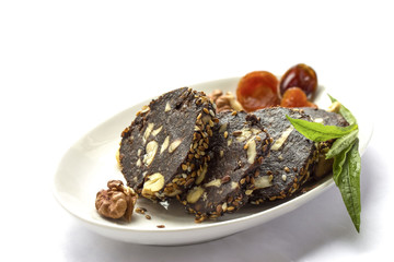 Chocolate cut sausage with dried fruits and nuts on a plate