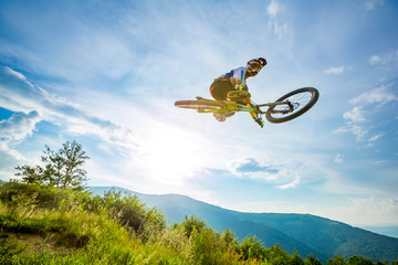 Professional rider is jumping on the bicycle, with background of blue sky. Sunny summer day.