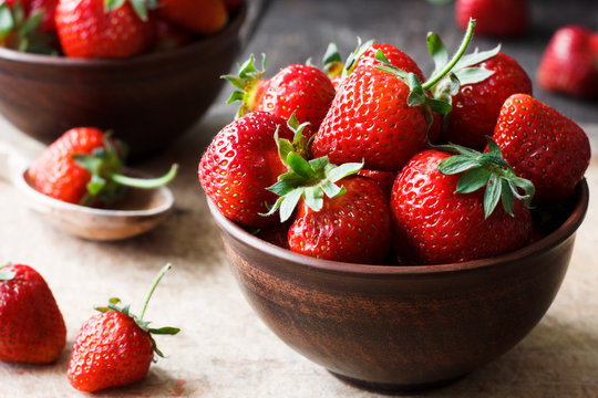 Fresh strawberry in a bowl on a wooden background