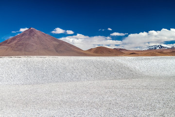Borax deposits at Laguna Colorada lake with mountain peaks in the background, Bolivia