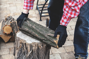 Male hand putting piece of wood on stump