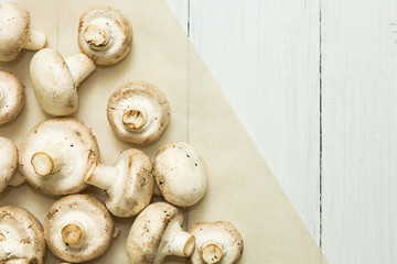 Fresh organic white mushrooms on a white wooden background, top view, space for text.