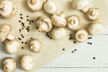 Fresh farmer organic mushrooms and bell pepper on a white wooden table, top view.