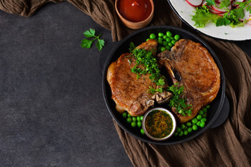 Steak grilled with a garnish of green peas and tomato sauce in a cast-iron frying pan