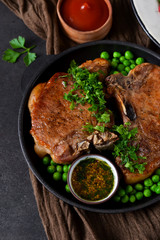 Steak grilled with a garnish of green peas and tomato sauce in a cast-iron frying pan