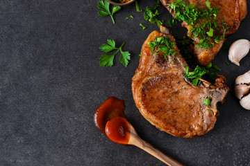 Juicy grilled pork steak with pesto sauce and tomato sauce on a black background