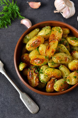 Young fried potatoes with garlic and dill on a black background