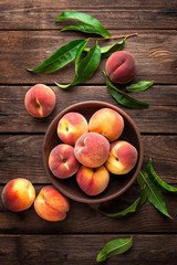 Fresh juicy peaches with leaves on dark wooden rustic background