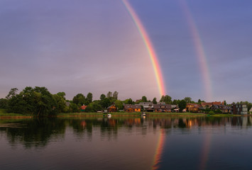 Summer landscape with double rainbow  over the lake Galve, near of Trakai Island Castle,  Lithuania. Water landscape with boats, township, green trees and lake under the sky with clouds and rainbow - Powered by Adobe