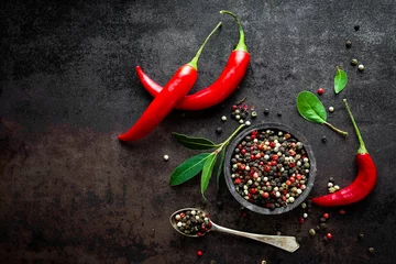 Foto op Canvas Red hot chili pepers en peperkorrels op zwarte metalen achtergrond, bovenaanzicht © Sea Wave