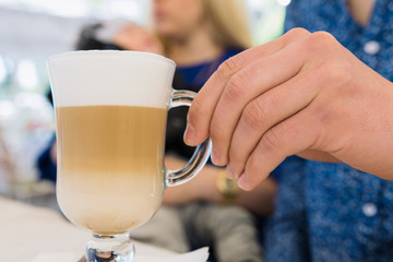 A man takes a cappuccino with white foam