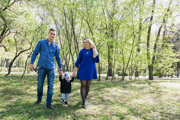 Naklejka na ściany i meble Happy young family spending time together outside in green nature