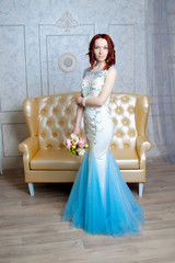 Beautiful young girl in evening dress posing at interior photo studio