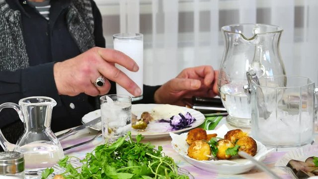 Man drinks Raki and eats meze. Senior man sits on dining table. If you like liqueur and anise, you will definitely love the taste of Raki alcoholic drink, made of grapes and raisins using the twice-di