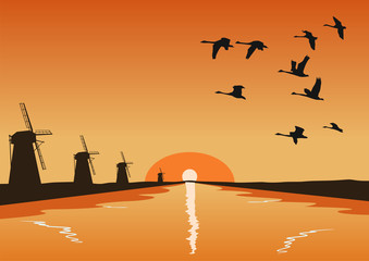 Fototapeta na wymiar Flock of geese flying over river with mills at sunset