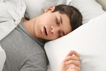 Handsome young man sleeping in bed at home