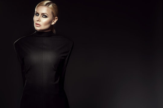 Portrait of charming blond model with pulled back hair and smoky eye make-up wearing male jacket back to front with her arms tied behind her back. Gender inequality concept. Copy-space