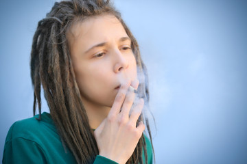 Young boy smoking weed on light background