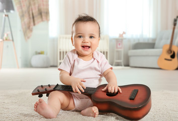 Cute little baby with guitar at home