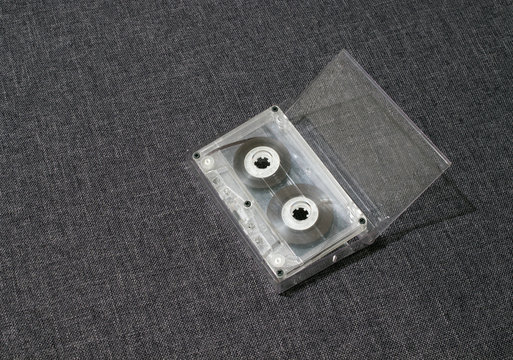Old worn scratched audio tape on a gray background in a box