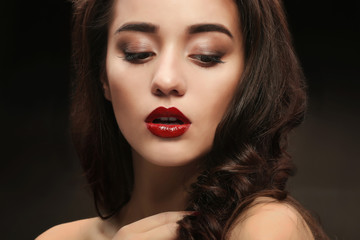 Fototapeta premium Portrait of beautiful woman with red lips on dark background