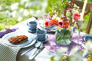 Rolgordijnen Table serving with blooming bouquet of flowers in garden © Africa Studio