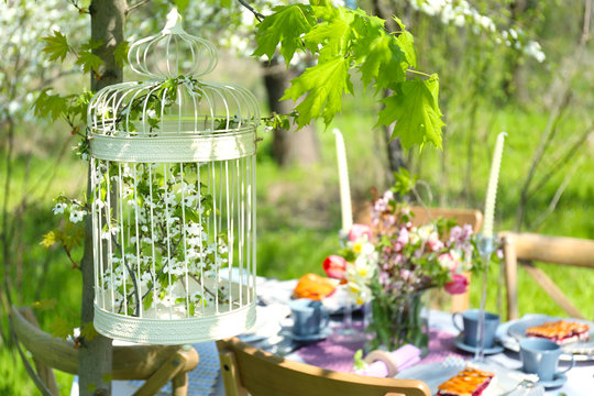 Decorative cage hanging from tree on blurred background