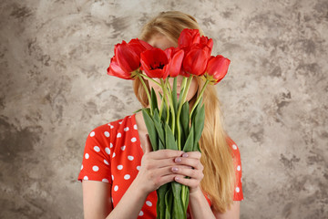 Beautiful young woman with bouquet of tulips on color background