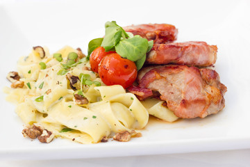 Bacon wrapped meat with pasta on white plate