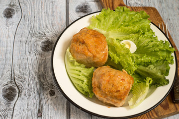  Chicken souffle.   Chicken souffle and leaves of fresh green salad on a white plate on a gray wooden background.