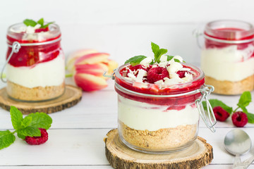Layered dessert with crumble, white vanilla cream and raspberry. White chocolate and fresh mint leaves on top.