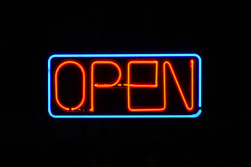 Neon OPEN sign in a window with a dark background.