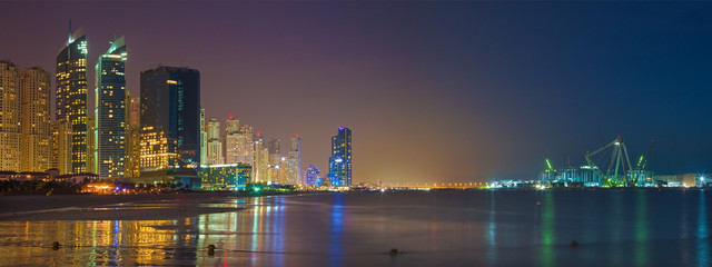 Dubai -  The nightly skyline panorama of Marina towers and worlds largest Ferris wheel under construction.