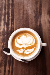 Cup of coffee with latte art on wooden background