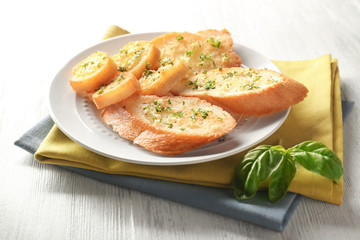 Plate with tasty garlic French bread slices and green napkin