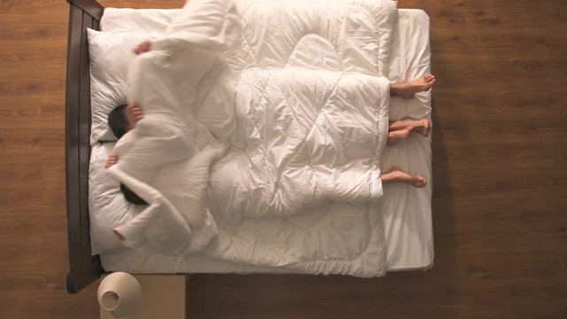 The happy couple have a sex under duvet. view from above