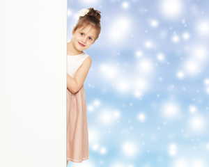 A little girl peeks out from behind the banner.