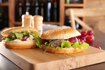 Wooden board with chicken salad in burger buns on table