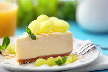 Tasty cheesecake slice with grapes on plate