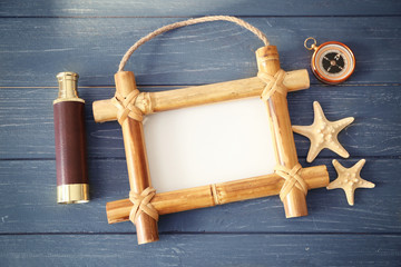 Travel concept. Bamboo frame with space for text, spyglass and compass on wooden background