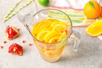Glass jug with refreshing citrus fruits cocktail on light background