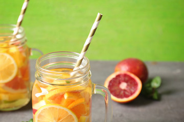 Glass mug with refreshing citrus fruits cocktail on table