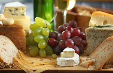 Wooden board with variety of cheese on table