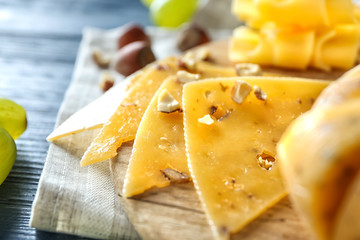 Wooden board with sliced cheese on table